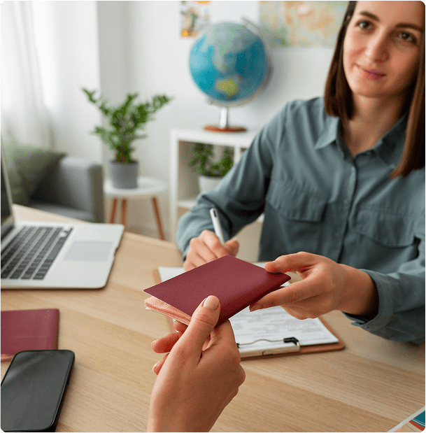 A smiling woman hands a passport to a student, signifying the start of their academic journey in New Zealand.