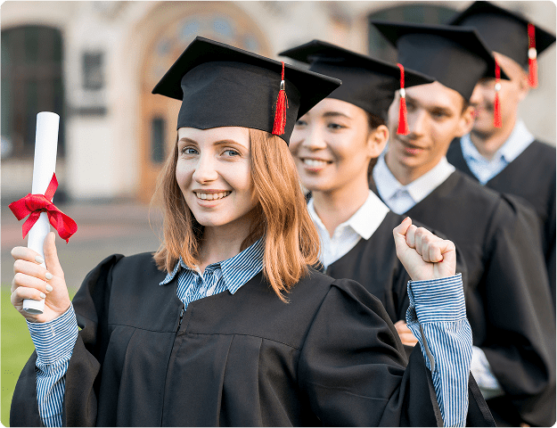 Graduates in caps and gowns celebrating their success with diploma in hand on a university campus.